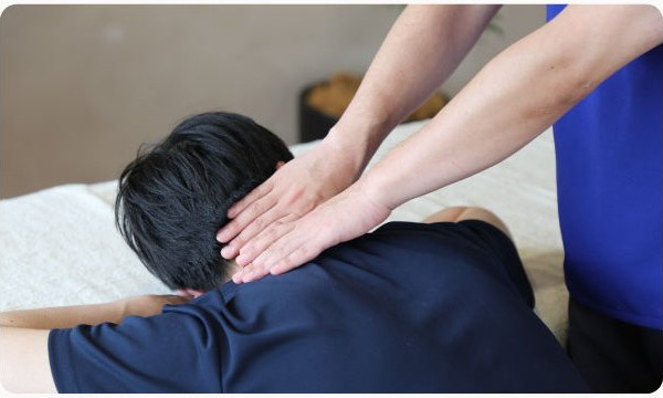 うつ伏せのお客様の背中を施術するスタッフ