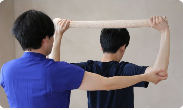 タオルを使ったストレッチを指導するスタッフ